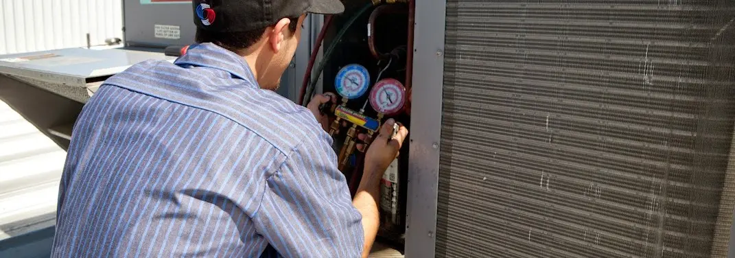 HVAC technician servicing a condenser unit in Wharton