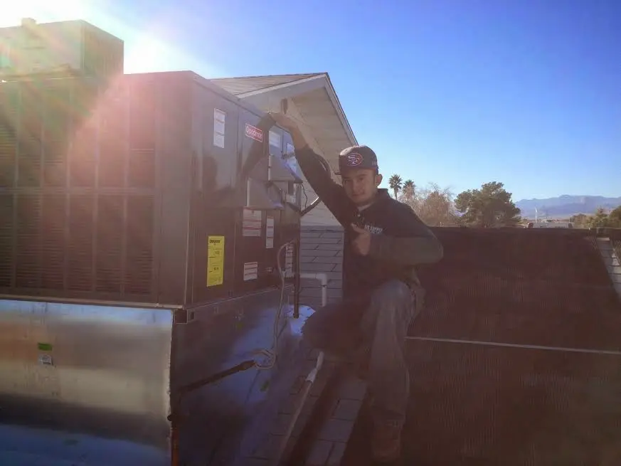 HVAC technician performing Air Duct Repair on a rooftop unit in Wharton